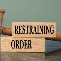 RESTRAINING ORDER - words on wooden blocks with a judge's gavel in the background