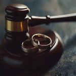 Judge gavel striking down wedding rings symbolizing divorce